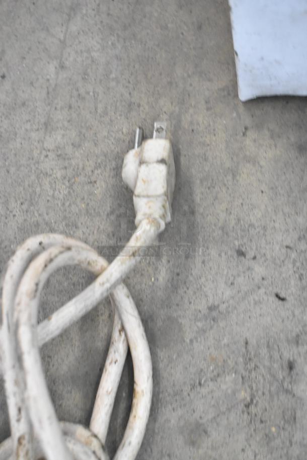 Coiled white power cord for the Magic Pop DMP-1 rice cake machine, showing wear and minor dirt accumulation.