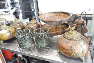 9 decorative items including ornate metal risers, patina vases, and a fish-embossed container, in good condition.
