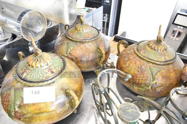 Nine decorative items, including intricately designed vases with embossed fish motifs and metal risers. Auction lot number 144 visible.