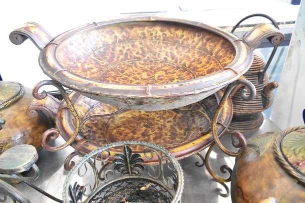 Nine assorted decorative items including a detailed vase and ornate risers. Wrought iron and ceramic materials. Rustic finish.