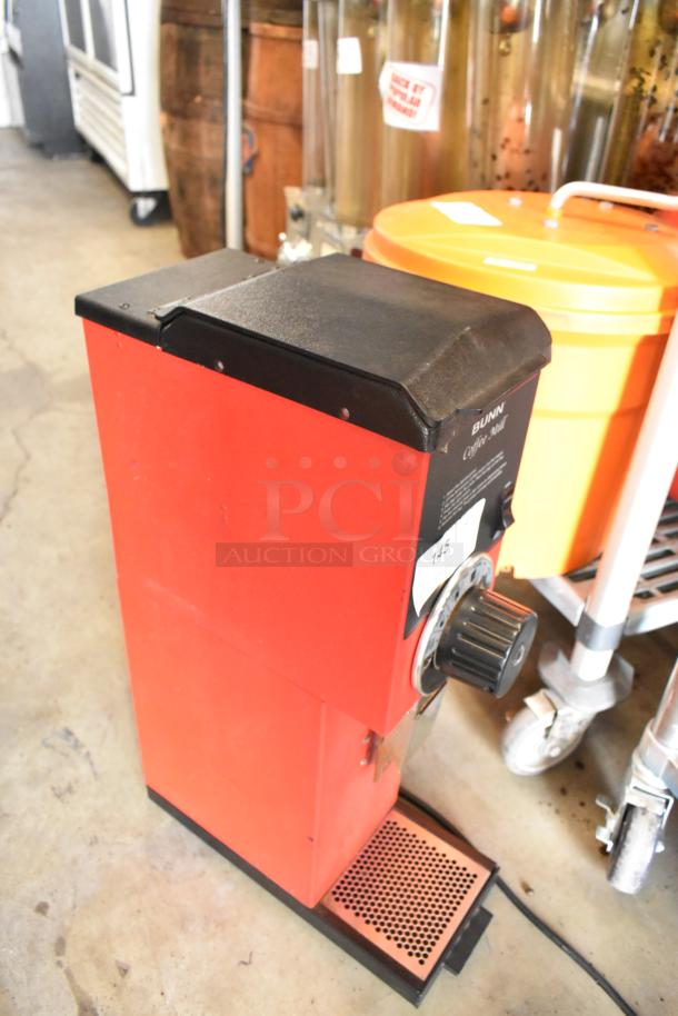 Bunn metal commercial countertop coffee bean grinder, red, 120 volts, 1 phase, with adjustable grind settings and visible wear.