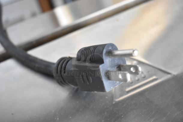 Plug of Winco EPG-1 Panini Press, showing three-prong plug on stainless steel background.