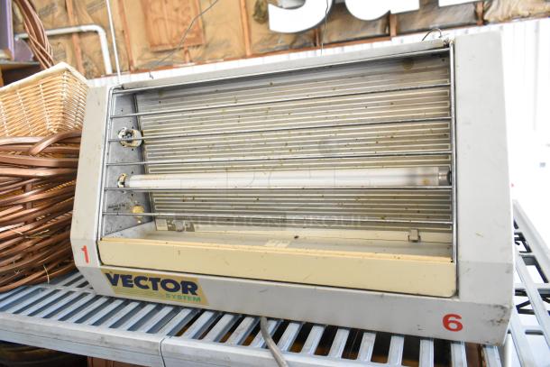 Vector E123180 bug zapper with visible wear, alongside wicker baskets. Label reads "Vector System." Bidding multiplies by three.
