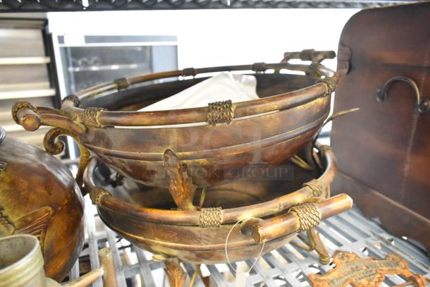 Bronze decorative bowls with intricate handles stacked next to a vintage wooden chest; part of a mixed tier lot.