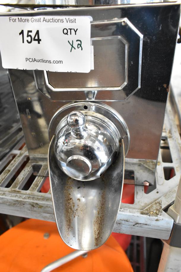 Two metal dry dispensers with shiny chrome finish, built-in scoop, slight rusting, labeled "154 QTY x2" from PCIAuctions.com.