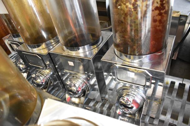 6 metal dry dispensers with clear containers, chrome finish. Ideal for cereals or grains. Good condition, sturdy build.
