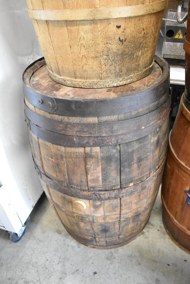 Four wooden barrels with metal bands, showing wear and patina. Sturdy construction, suitable for storage or decor.