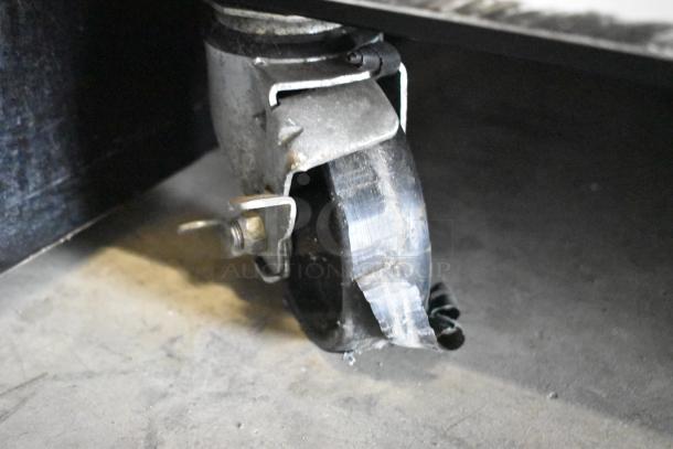Close-up of a commercial caster wheel from a Turbo Air TGF-49F freezer, showing metal and poly material, slight wear visible.