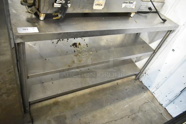 Stainless steel table with two under shelves, used condition, minor surface debris, suitable for storage or kitchen use.
