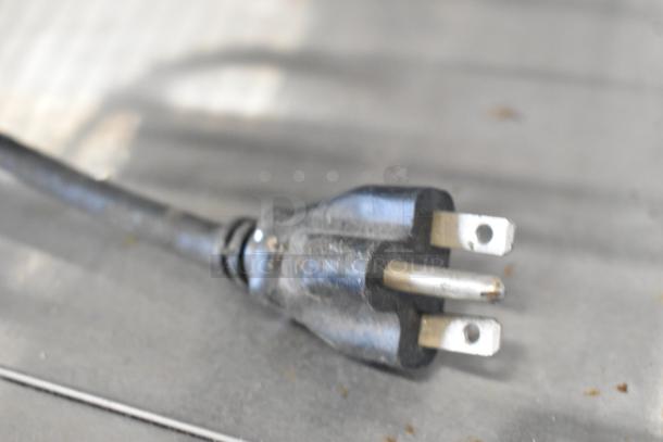 Close-up of black power plug for Waring WCT825 toaster, showing three-prong design; part of a stainless steel countertop appliance.