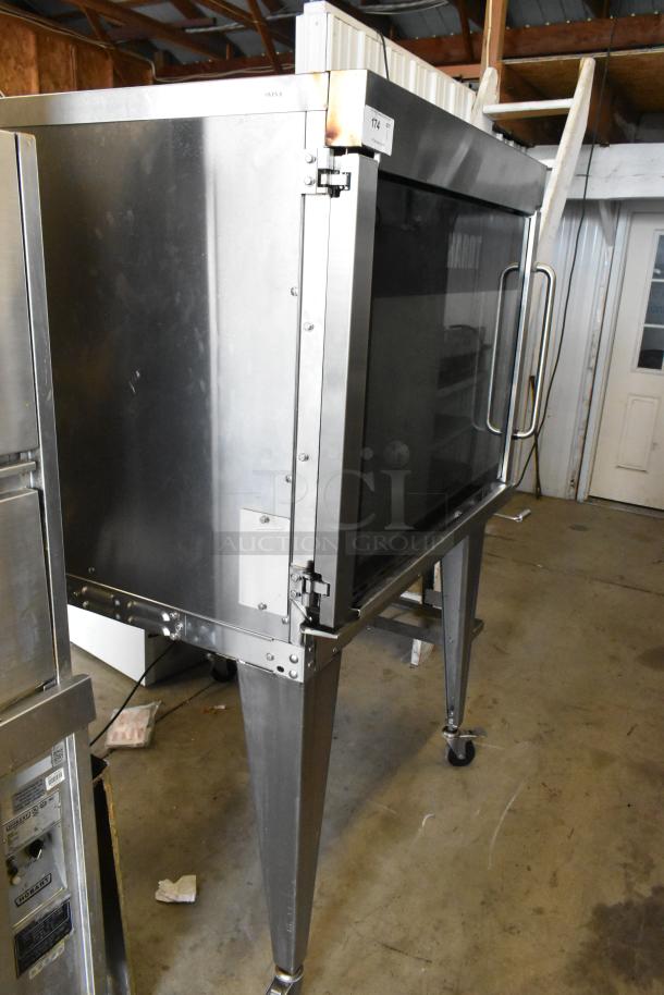 Hardt GC/4000 stainless steel rotisserie oven, natural gas powered, on metal legs with commercial casters. Slight wear visible.