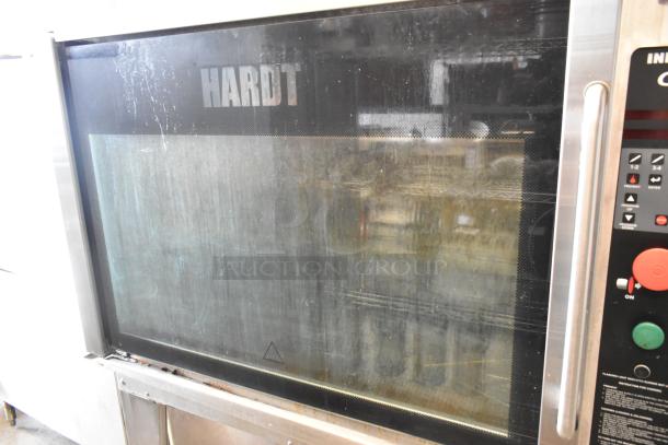 Hardt GC/4000 stainless steel rotisserie oven, natural gas-powered, on metal legs with commercial casters. Visible wear on glass.