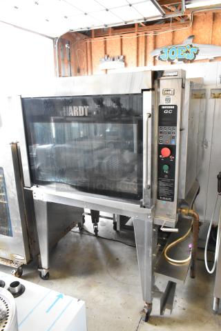 Hardt GC/4000 stainless steel rotisserie oven, natural gas powered, on metal legs with commercial casters, in good condition.