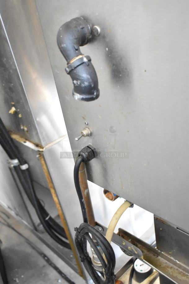Hardt GC/4000 natural gas rotisserie oven, stainless steel, on metal legs with casters. Connections visible.