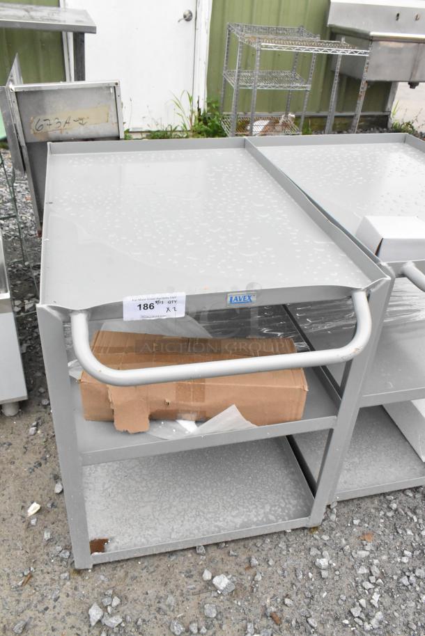 Gray metal 3-tier cart with visible scratches and dents, brand new. Labeled "Avex." Some packaging materials shown.