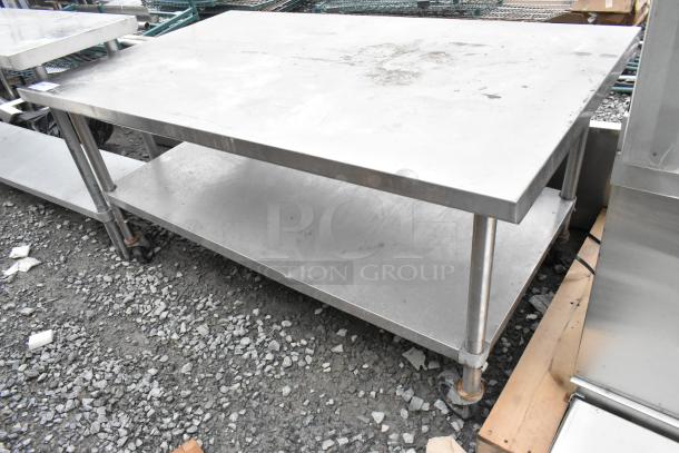 Stainless steel table with metal under shelf, on commercial casters, shown outdoors, minor surface wear visible.