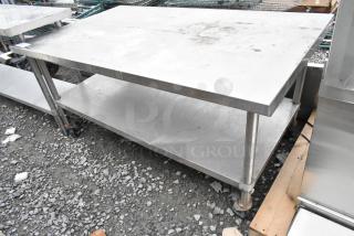 Stainless steel table with metal under shelf, on commercial casters, shown outdoors, minor surface wear visible.