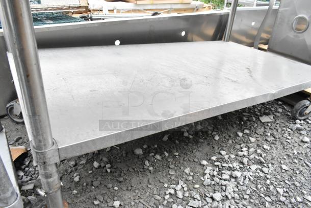 Stainless steel table with metal under shelf, commercial casters, in used condition, ideal for kitchen or industrial use.