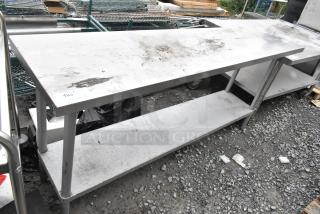 Stainless steel table with metal under shelf, used condition, surface wear, ideal for commercial use.