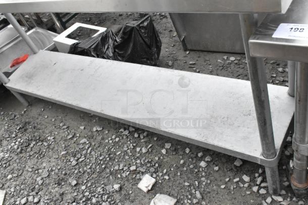 Stainless steel table with metal under shelf, showing signs of use. Ideal for industrial or kitchen settings.