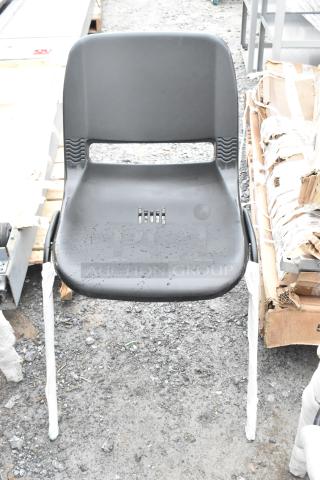Black poly and metal chair, brand new with minor scratches and dents, sturdy design, unwrapped legs, outdoor setting.