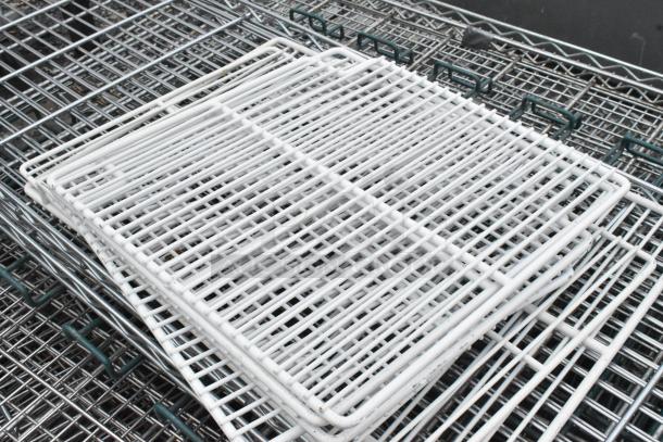 Lot of various wire shelves, including white and chrome, stacked together. Suitable for storage solutions.