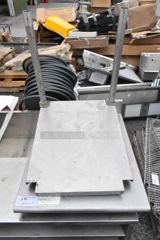 Stainless steel tabletop with under shelf and two legs, minor wear, label indicating "The Finishing Touch" and quantity "210".