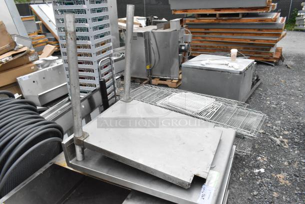 Stainless steel tabletop and undershelf with 2 legs, used; visible wear and scratches, suitable for industrial or kitchen use.