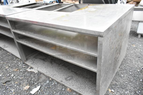 Stainless steel counter with cut-out, featuring three under shelves. Used condition, ideal for kitchens or workshops.