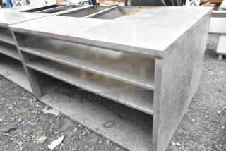 Stainless steel counter with cut-out, featuring three under shelves. Used condition, ideal for kitchens or workshops.
