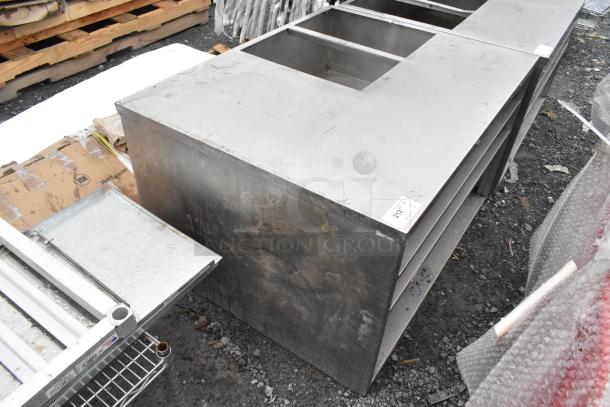 Stainless steel counter with a cut-out and three under shelves, showing signs of wear. Item tag "222" is visible.