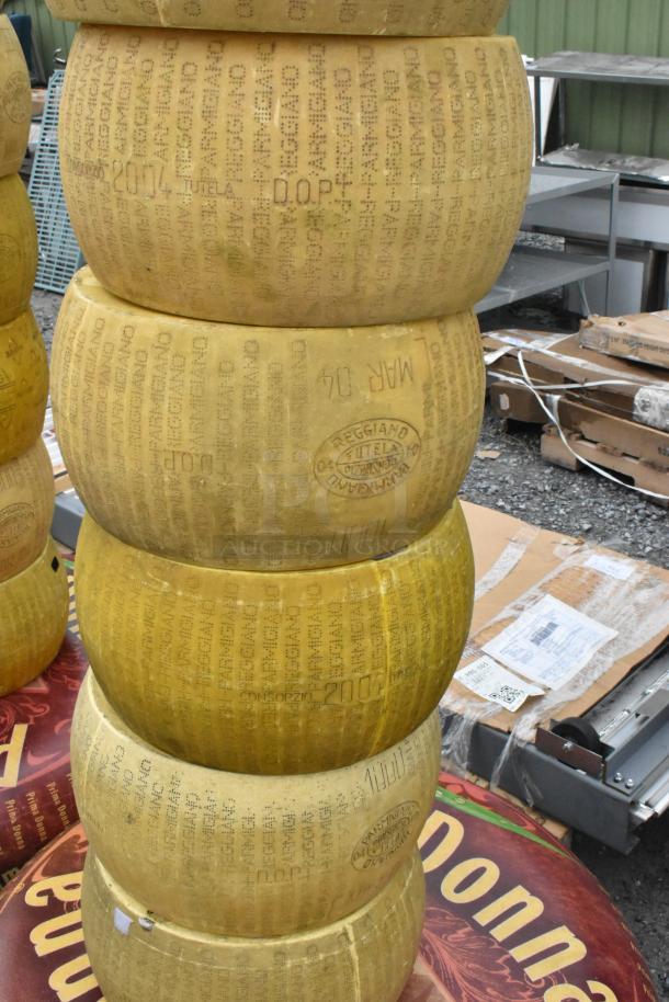 Stack of 14 decorative cheese wheels with "Parmigiano Reggiano" markings, suitable for displays or events.