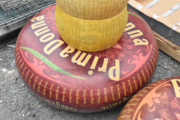 Stacked cheese wheel decorations, featuring "Prima Donna" and Italian writing. Two visible distinct designs. Labels suggest decorative use.