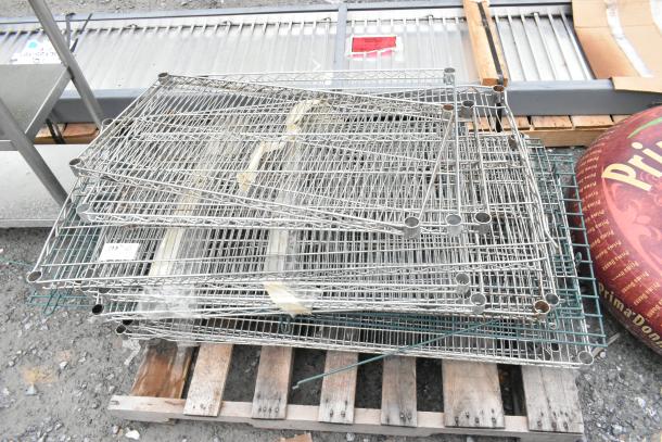 Lot of various metal wire shelves stacked on a wooden pallet, in used condition with visible metal brackets.