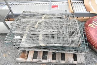Lot of various metal wire shelves stacked on a wooden pallet, in used condition with visible metal brackets.