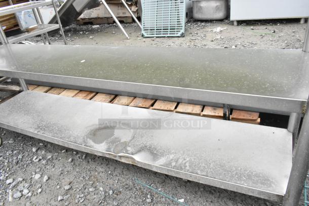 Stainless steel table with two under shelves, surface shows wear and rust. Ideal for kitchen or industrial use.