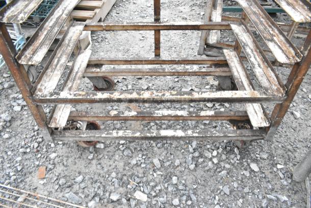 2 metal commercial pan transport racks with top guide for rack oven, on industrial casters, showing visible wear.