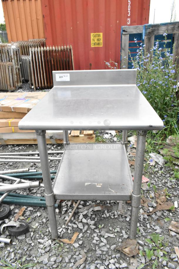 Stainless steel table with metal under shelf. Used condition, durable, has label "221" on top. Ideal for industrial use.