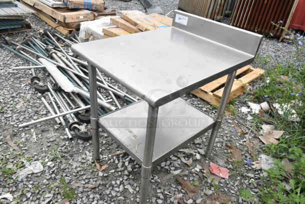 Stainless steel table with back splash and metal under shelf, in used condition, tag labeled "221".