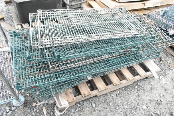 Lot of 2 pallets with assorted wire shelves and poles, in varied condition, stacked on wooden pallets. Suitable for storage use.