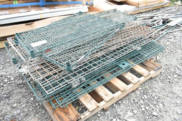 Lot of 2 pallets with various metal wire shelves and poles, used condition, stacked on wooden pallets outdoors.