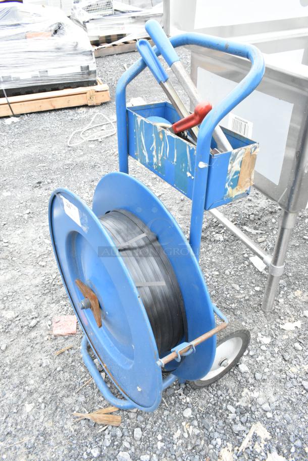 Blue metal pallet banding cart with contents, featuring sturdy wheels and handles, used condition.