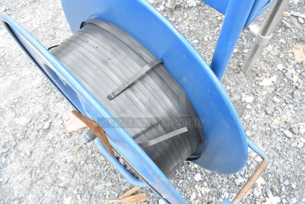 Blue metal pallet banding cart with strapping reel, in used condition. Includes black plastic banding.