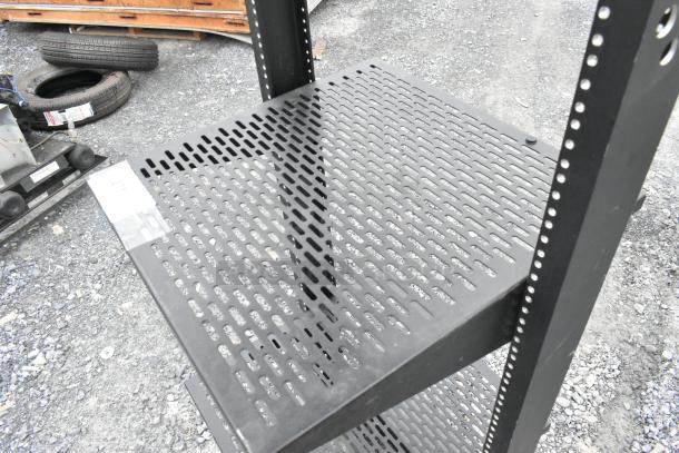 Black metal shelving unit with perforated shelves, sturdy construction, and adjustable height. Slight wear visible.