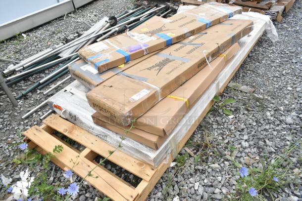 Stack of brand new scratch and dent items, including multiple boxed stainless steel overshelves on a pallet. Various markings visible.