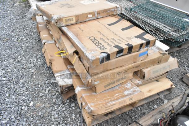 Stack of brand new scratch and dent boxes including Regency stainless steel work table, outdoor white table, and wall shelf.