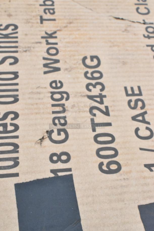 Cardboard box showing "18 Gauge Work Table, 600T2436G". Packaging appears scratched, indicating content condition.