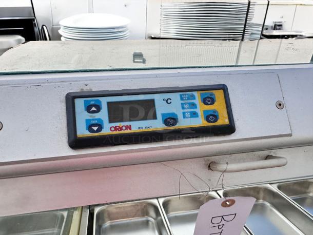 Control panel of an Orion refrigeration unit showing temperature controls and settings. Tag attached indicates item details.