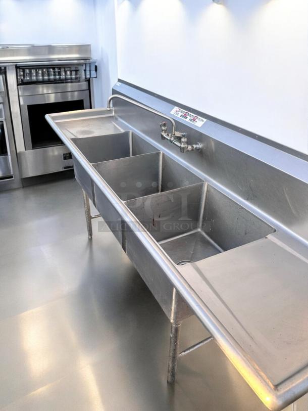 Stainless steel 3-compartment sink with dual drainboards, 96" x 31". Excellent condition, fully tested and working.