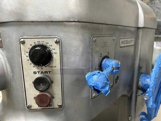 Hobart H600T 60QT dough mixer close-up showing start/stop controls and speed settings with tape protection.